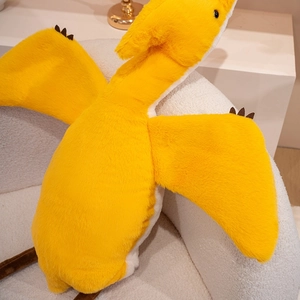 Close-up detail of a soft yellow pterodactyl plush toy showing fuzzy texture and wings