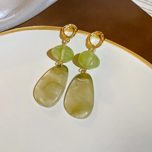 Detail of drop earrings with gold rings, green beads, and marble resin waterdrop charms