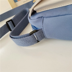 Macro detail of canvas shoulder bag showing blue and white fabric texture and stitching