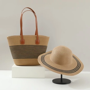 Close-up of woven straw tote and wide brim sun hat with elegant black stripe detail