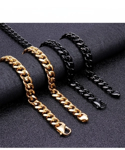 Detail of gold and black Cuban link necklaces with polished lobster clasps on fabric