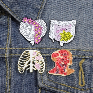 Set of four anatomical enamel pins featuring floral ribs and heart on denim fabric