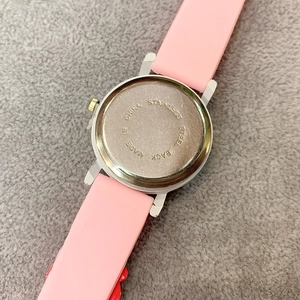 Detail of the stainless steel back of pink strawberry watch on grey felt background