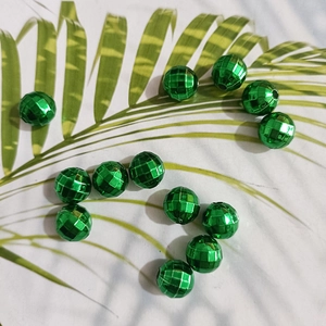 Macro detail of faceted green beads on a palm leaf for DIY jewelry making