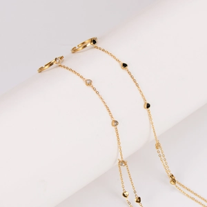 Gold finger bracelet featuring adjustable rings and heart-shaped charms with black accents