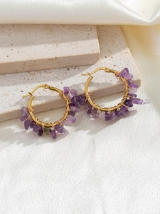 Detail of handmade bohemian gold wire wrapped hoop earrings with purple natural stones