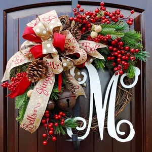 Christmas wreath with red berries pine cones bells and personalized letter M on wooden door