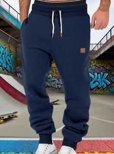 Men's navy jogger pants with drawstring waist shown in a street graffiti skatepark setting