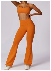 Detail of high-waist flared yoga pants and sports bra in vibrant orange stretch fabric