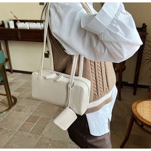 Detail of a cream faux leather handbag with a matching mini square coin purse pendant