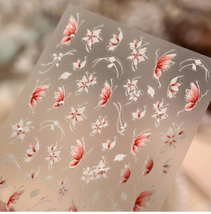 Detailed macro of 3D butterfly and floral nail art decals with pearl accents