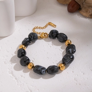 Detail of irregular black resin beads and gold accents on a beaded starfish bracelet