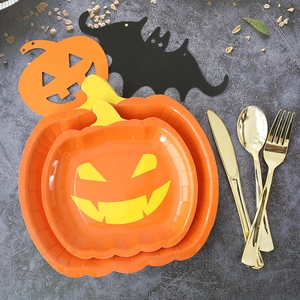 Close-up of orange pumpkin paper plates with gold cutlery for Halloween party decor