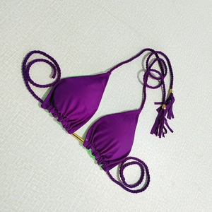 Detail of purple bikini top with neon green lining and braided straps with tassels