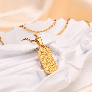 Macro view of gold celestial rectangle pendant with sun and moon tarot motifs