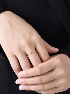 Macro detail of 1mm gold stainless steel ring with colorful zircon stones on model's hand