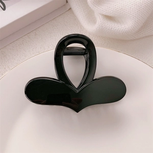 Minimalist black heart claw clip displayed on a white tray with a soft knit background