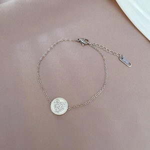 Macro detail of silver stainless steel chain bracelet with crystal pave heart charm