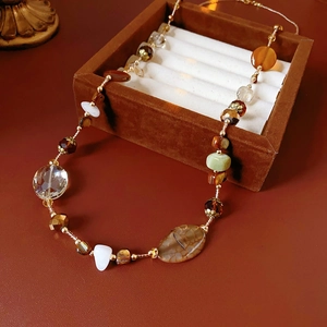 Detail of beaded necklace with agate and white marble on brown velvet and leather