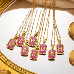 Golden titanium steel necklace with purple glitter square initial pendants shown on mirror