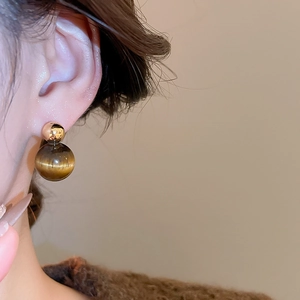 Detail view of tiger eye stone drop earring on model featuring gold and textured beads