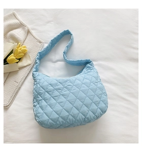 Blue quilted nylon cloud shoulder bag shown from above with yellow tulip flowers