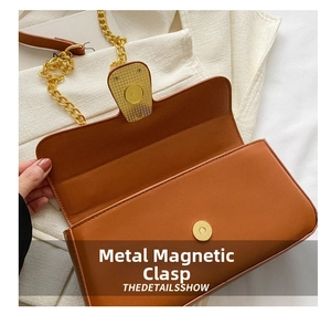 Detail view of the magnetic hardware snap and golden chain on a brown shoulder bag