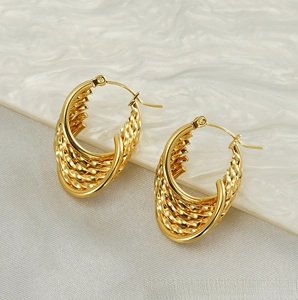 Macro view of gold-plated multi-layer woven hoop earrings with vintage texture