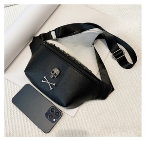 Detail of black leather waist bag with metal skull ornament and silver rivet zippers