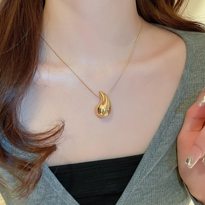 Close-up of a minimalist gold teardrop pendant necklace worn by a model