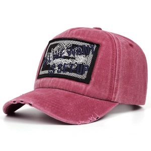 Close-up of distressed berry red baseball cap with embroidered patch and worn brim details