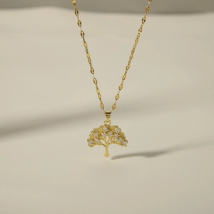 Close-up of a gold tree of life pendant with zircon inlay on a delicate flat chain