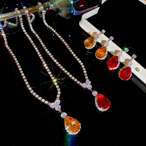 Detailed view of teardrop zircon necklace and earrings set in amber and ruby red tones