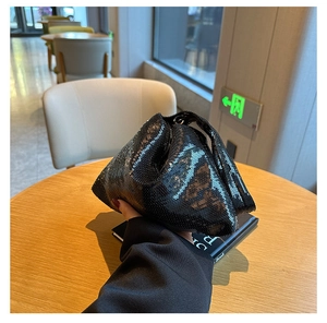 Détail de la texture des paillettes noires sur un sac de soirée triangulaire