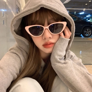 Pink cat eye sunglasses with black lenses worn by a model in a stylish indoor setting