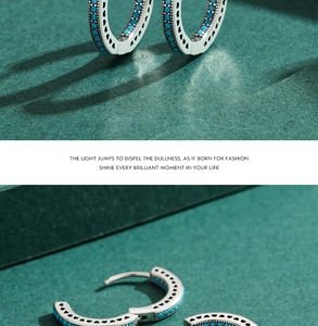 Detail of silver hoop earrings with turquoise beads and hollow heart patterns