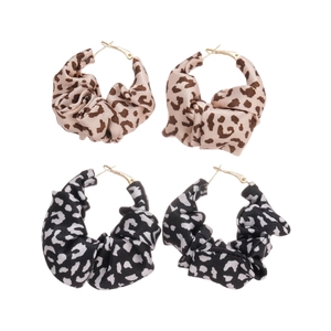Two pairs of leopard print fabric hoop earrings in beige and black displayed on white
