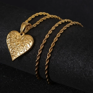 Detail of vintage gold heart pendant with intricate relief and twist chain link