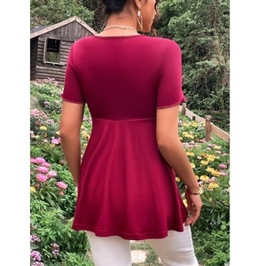 Detail of burgundy maternity tunic featuring high waist ruffle hem in a garden setting