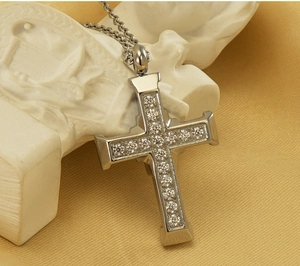 Macro shot of silver-toned stainless steel cross pendant with micro-pave clear zircon stones