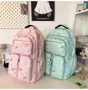 Detail of pink and green cute bear backpacks with multiple zipper pockets on a desk
