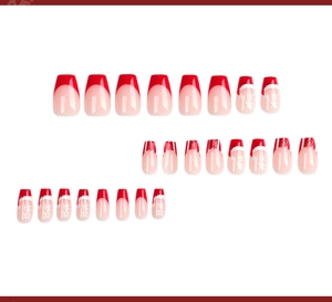 Macro view of Christmas press-on nails featuring red French tips and festive patterns