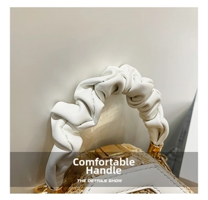 Detail of woven straw handbag featuring a white ruched leather handle and gold hardware