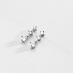 Macro shot of silver S925 earrings featuring three clear cubic zirconia stones in a row