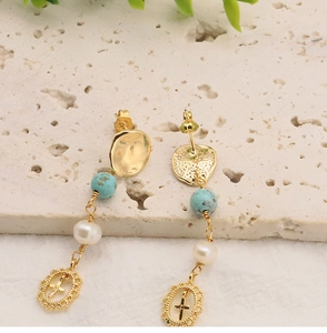 Gros plan des boucles d'oreilles croix dorées avec pierres turquoise et perles