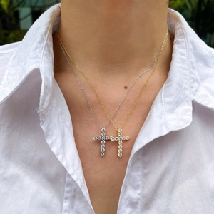 Detailed macro view of layered gold and silver cross necklaces with opal shell beads
