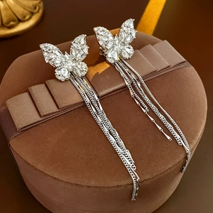 Detailed view of silver butterfly ear cuff with zircon tassels on a premium jewelry box