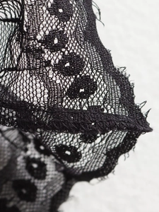 Close-up detail of the elegant black lace patchwork fabric on the straight leg trousers