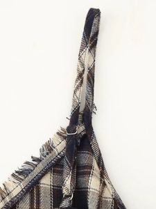 Detailed view of plaid fabric dress with raw fringe edges and slim shoulder straps