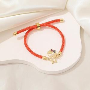 Dettaglio del bracciale intrecciato rosso con ciondolo a bambina dorata e cristalli colorati